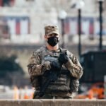 man in black and brown camouflage uniform holding rifle