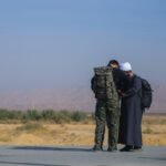 man wearing camouflage soldier uniform besides man wearing white turban
