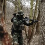 soldier holding assault rifle in forest